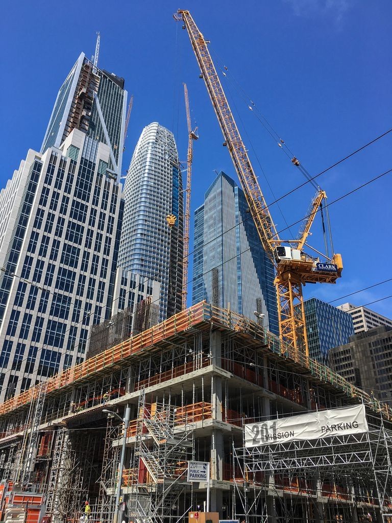 Urban construction site with a tower crane rising against a city skyline